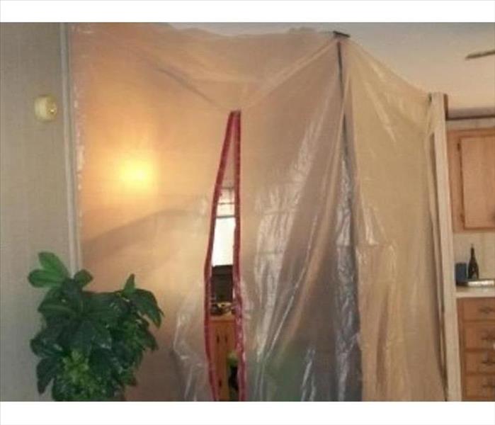poly plastic film with a zipper opening is taped between two walls in a residential home.